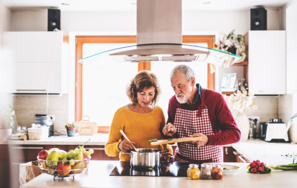 Senior couple preparing food in the kitchen with a solid surface countertop