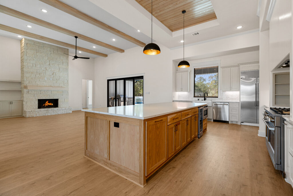 Sleek modern kitchen with durable wood-look vinyl flooring and classic white herringbone subway tile backsplash and cabinets by Degraaf in Grand Rapids, MI.